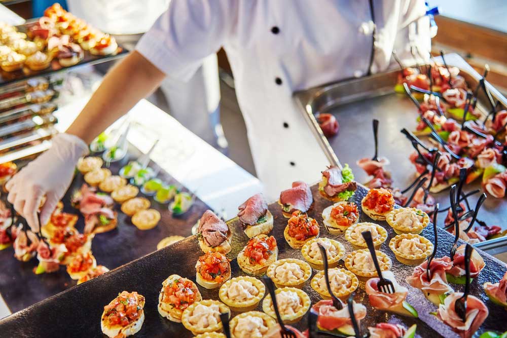 A chef placing small, bite-sized dishes on a serving tray