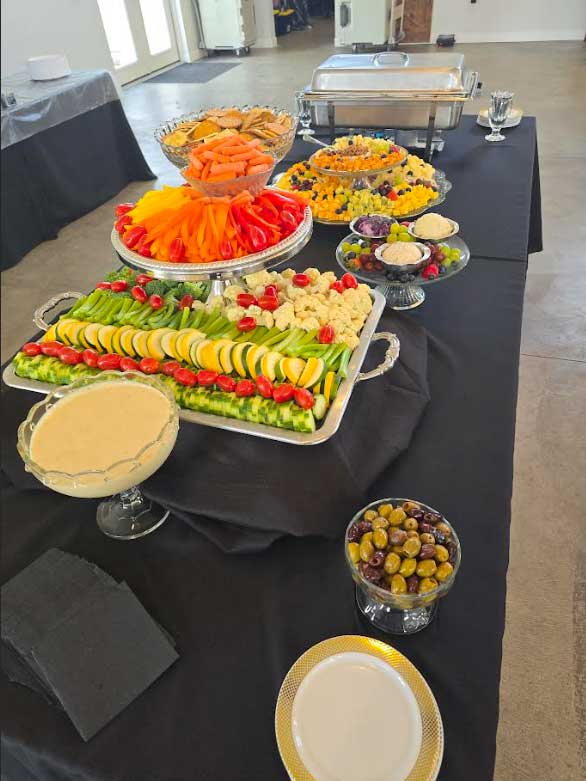 A banquet table covered with platters and trays of various sizes covered with fruits and vegetables