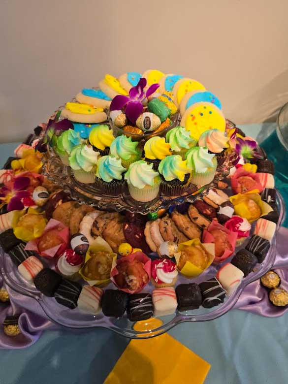 A round, two-layer serving tray covered with cupcakes, cookies, and fudge bites
